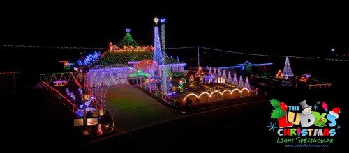 A colorful display of Christmas lights decorating a house and yard, featuring festive decorations and a starry night sky.