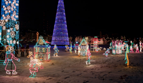 Colorful holiday lights illuminate a snowy scene with decorated trees and whimsical houses.