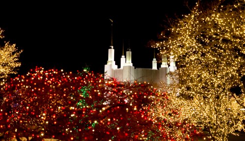 A brightly lit scene featuring a building with spires, surrounded by festive red and white holiday lights.