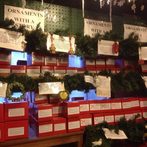 A display of red ornament boxes decorated with greenery and signs, showcasing various holiday ornaments.