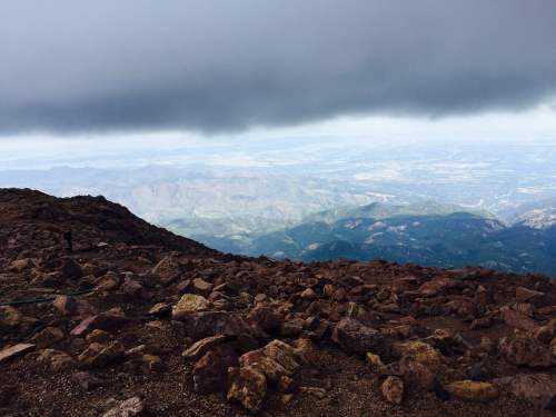 A rocky mountain landscape under a cloudy sky, with distant hills and valleys visible in the background.