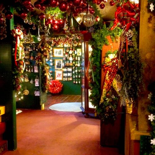 A festive room decorated with Christmas ornaments, garlands, and red and green accents, creating a cozy holiday atmosphere.