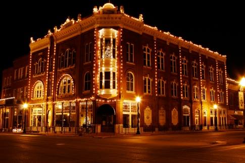 Historic brick building illuminated with string lights at night, showcasing its architectural details and charm.