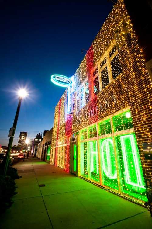 A brightly lit building decorated with colorful lights, glowing "HOL" sign, and a clear evening sky.