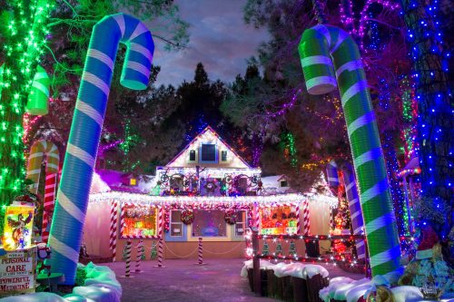 A festive scene featuring a brightly lit house decorated with colorful lights and oversized candy canes.