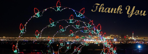 Colorful holiday lights arching over a city skyline at night with "Thank You" in elegant gold text.