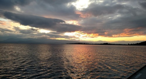 A serene sunset over a calm lake, with colorful clouds reflecting on the water's surface.