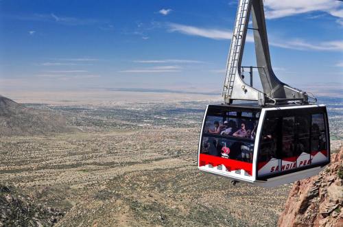 A cable car glides over a vast landscape, offering panoramic views of mountains and valleys below.