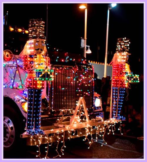 A festive truck adorned with colorful lights and nutcracker figures, illuminated at night during a parade.