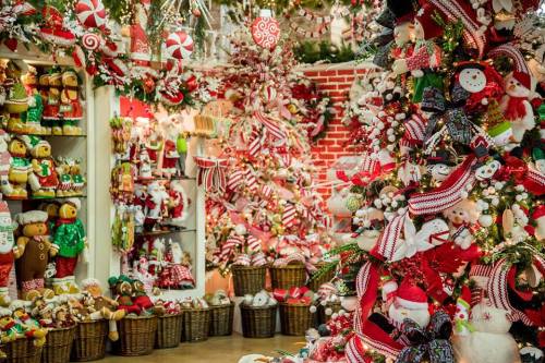 A festive holiday display filled with decorated Christmas trees, plush toys, and colorful ornaments.