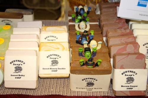 A display of various handmade soaps in different colors and scents, some topped with playful figurines.
