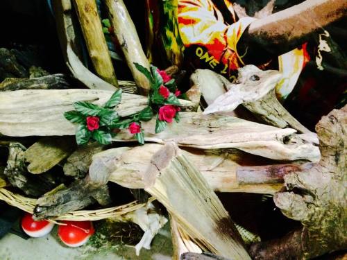 A pile of driftwood with a decorative arrangement of red roses and green leaves on top.