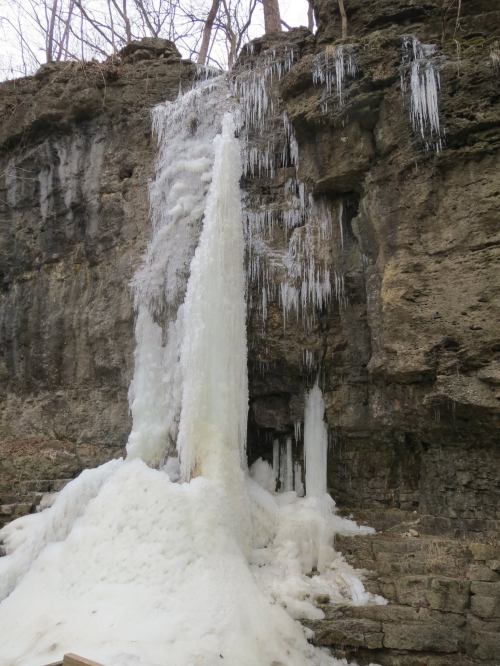 A frozen waterfall cascading down a rocky cliff, surrounded by icicles and snow.