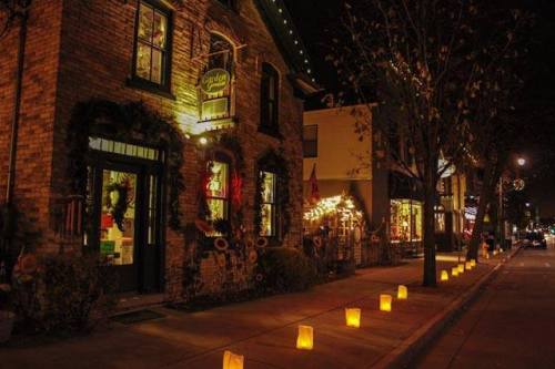 A charming street scene at night, featuring a brick building adorned with holiday decorations and glowing lanterns along the sidewalk.