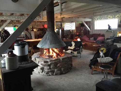 Cozy interior of a rustic space with a central stone fireplace, seating areas, and warm lighting.