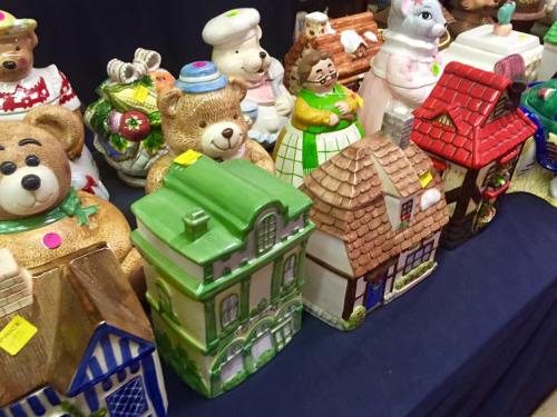 A colorful display of ceramic cookie jars shaped like bears, houses, and various whimsical characters.