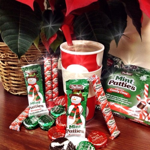 A festive arrangement of mint patties, candy canes, and a cup of hot chocolate surrounded by holiday decorations.