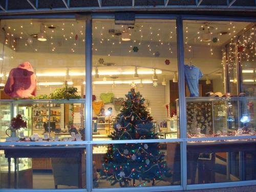 A festive store window decorated with a Christmas tree, lights, and holiday displays.