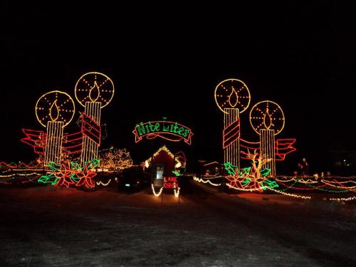 Colorful holiday lights display featuring large candles and festive decorations against a dark night sky.