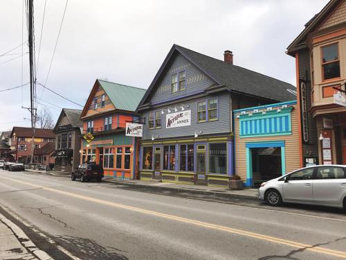 Colorful buildings line a street, featuring shops with unique facades and a cloudy sky overhead.