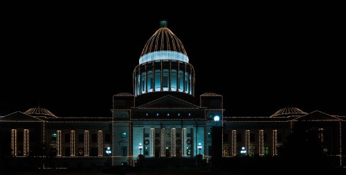The illuminated dome of a grand building at night, adorned with festive lights.