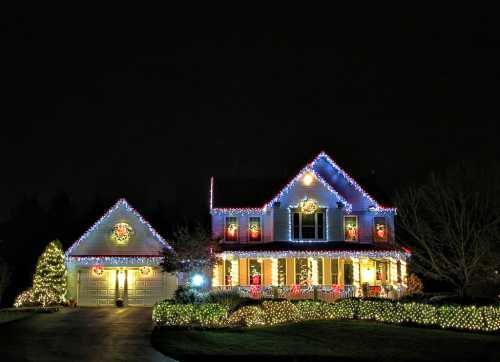 A beautifully decorated house at night, adorned with colorful Christmas lights and festive decorations.