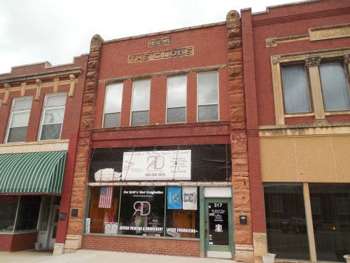 Historic brick building with "The Globe" sign, featuring storefronts and a banner for a local business.