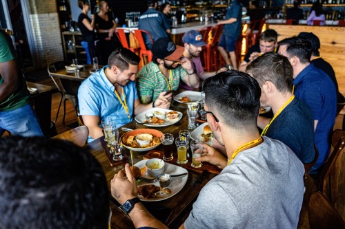 A group of men enjoying a meal together at a restaurant, with plates of food and drinks on the table.
