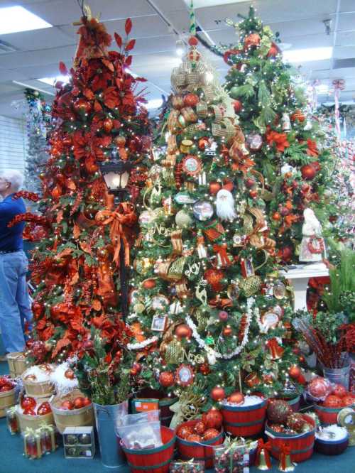 A festive display of decorated Christmas trees in red and gold, surrounded by ornaments and holiday decorations.