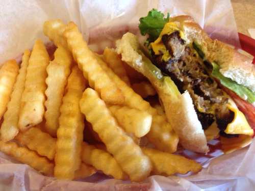 A plate featuring a cheeseburger with lettuce and tomato alongside a serving of crinkle-cut fries.