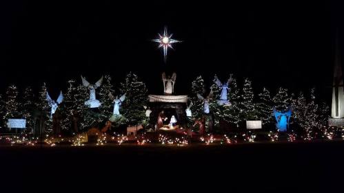 A festive display featuring illuminated angels, trees, and a star, creating a serene holiday scene at night.