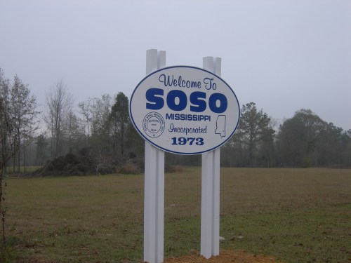 Welcome sign for Soso, Mississippi, with the year of incorporation, 1973, surrounded by trees and a cloudy sky.