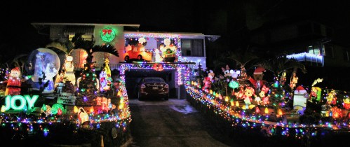 A brightly lit house decorated with colorful Christmas lights and festive inflatables, creating a cheerful holiday scene.