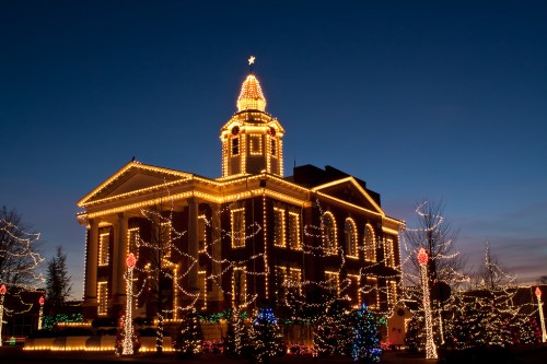 A beautifully lit historic building adorned with festive lights against a twilight sky.