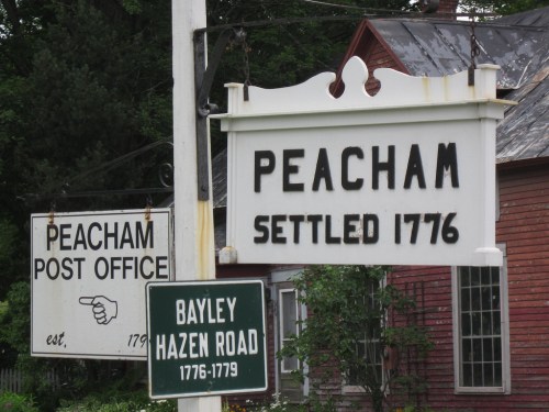 Signage for Peacham, Vermont, featuring "Peacham Settled 1776" and "Peacham Post Office" with historical dates.