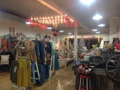 A cozy boutique interior featuring clothing racks, decorative items, and warm lighting.