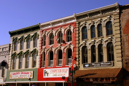 Historic buildings with ornate facades, featuring colorful exteriors and storefronts, in a vibrant urban setting.