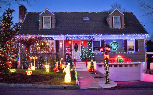 A festive house decorated with colorful Christmas lights and holiday decorations in the yard.