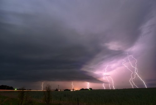 A dramatic sky filled with dark clouds and multiple lightning strikes illuminating the landscape below.