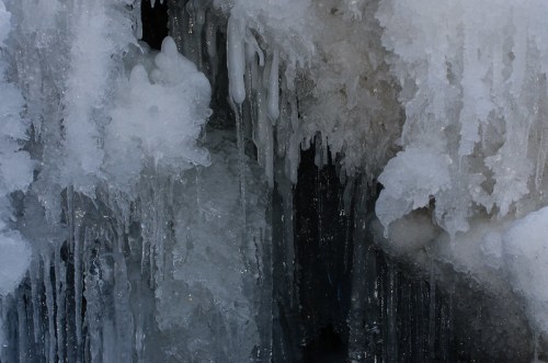 Close-up of icicles and frozen water formations, showcasing intricate ice textures and glistening surfaces.