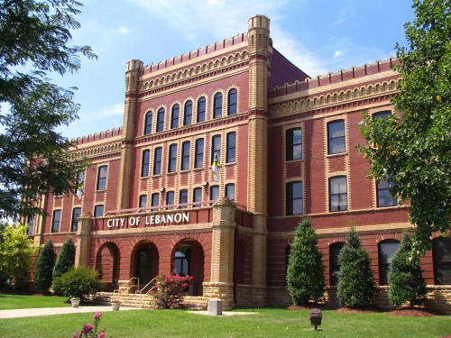 Historic red brick building with ornate architecture, featuring the words "City of Lebanon" and surrounded by greenery.
