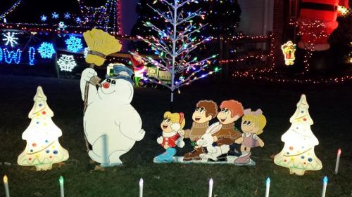 Colorful holiday display featuring cartoon characters, a snowman, and decorated trees with lights.