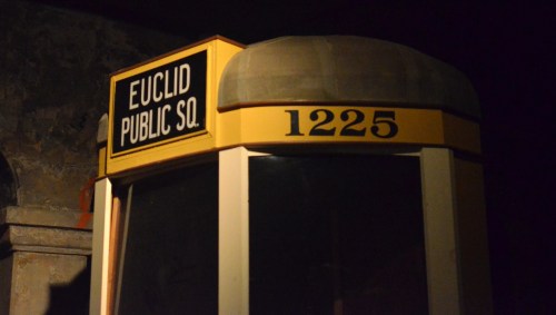 A vintage public phone booth with a sign reading "Euclid Public Sq." and the number "1225" on top.