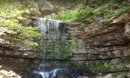A serene waterfall cascading over rocky cliffs, surrounded by lush greenery and moss.