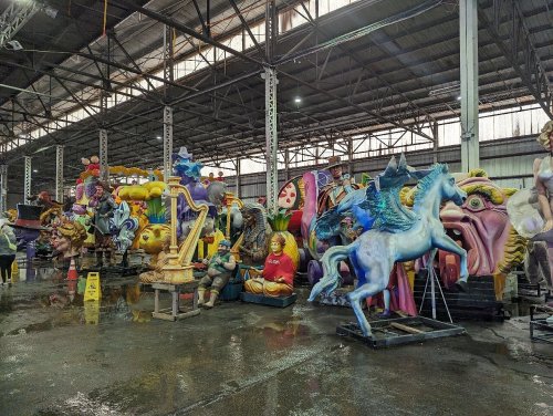 Colorful sculptures and figures displayed in a large warehouse, with various themes and characters visible.