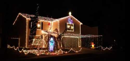 A house decorated with colorful Christmas lights, featuring a nativity scene and festive ornaments.