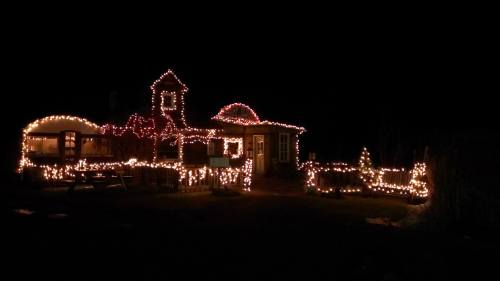 A house decorated with colorful Christmas lights, glowing warmly against a dark night sky.