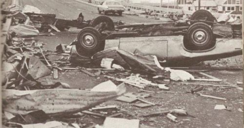 A chaotic scene of a car accident with an overturned vehicle and debris scattered on the road.