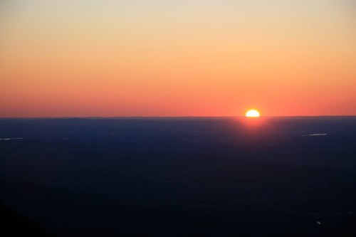 A vibrant sunset over a distant horizon, casting warm hues of orange and pink across the sky.