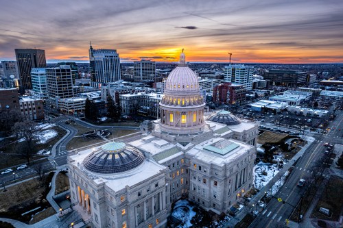 Aerial view of a city skyline at sunset, featuring a prominent dome building and urban landscape.